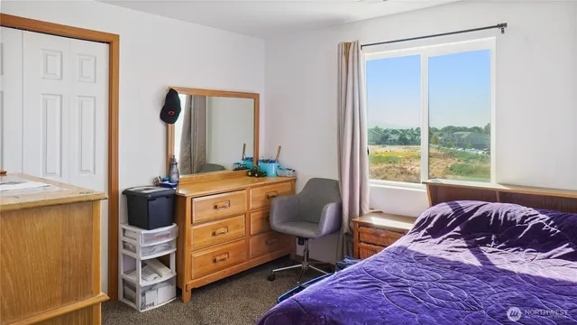 a bedroom with a bed and a dresser next to a window