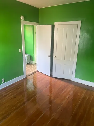 a view of an empty room with closet and wooden floor