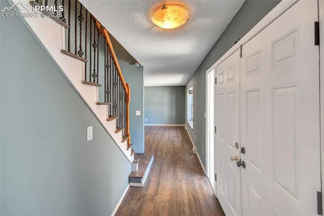 a view of a room with wooden floor chandelier and a kitchen