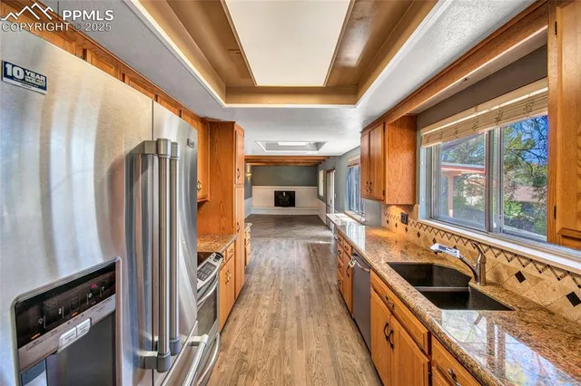 a kitchen with stainless steel appliances granite countertop a refrigerator a stove and a sink