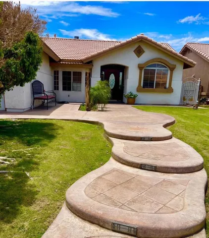 a view of a white house with a yard potted plants and a large tree