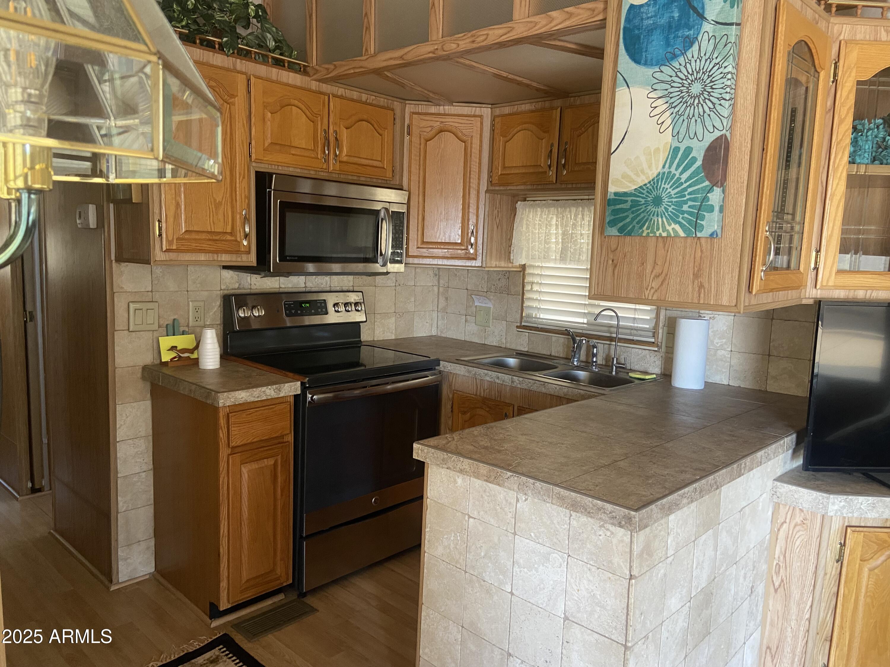 1206 West Klamath Avenue Apache Junction, AZ 85119 - Photo 10 of 35 a kitchen with a sink a microwave a stove and refrigerator