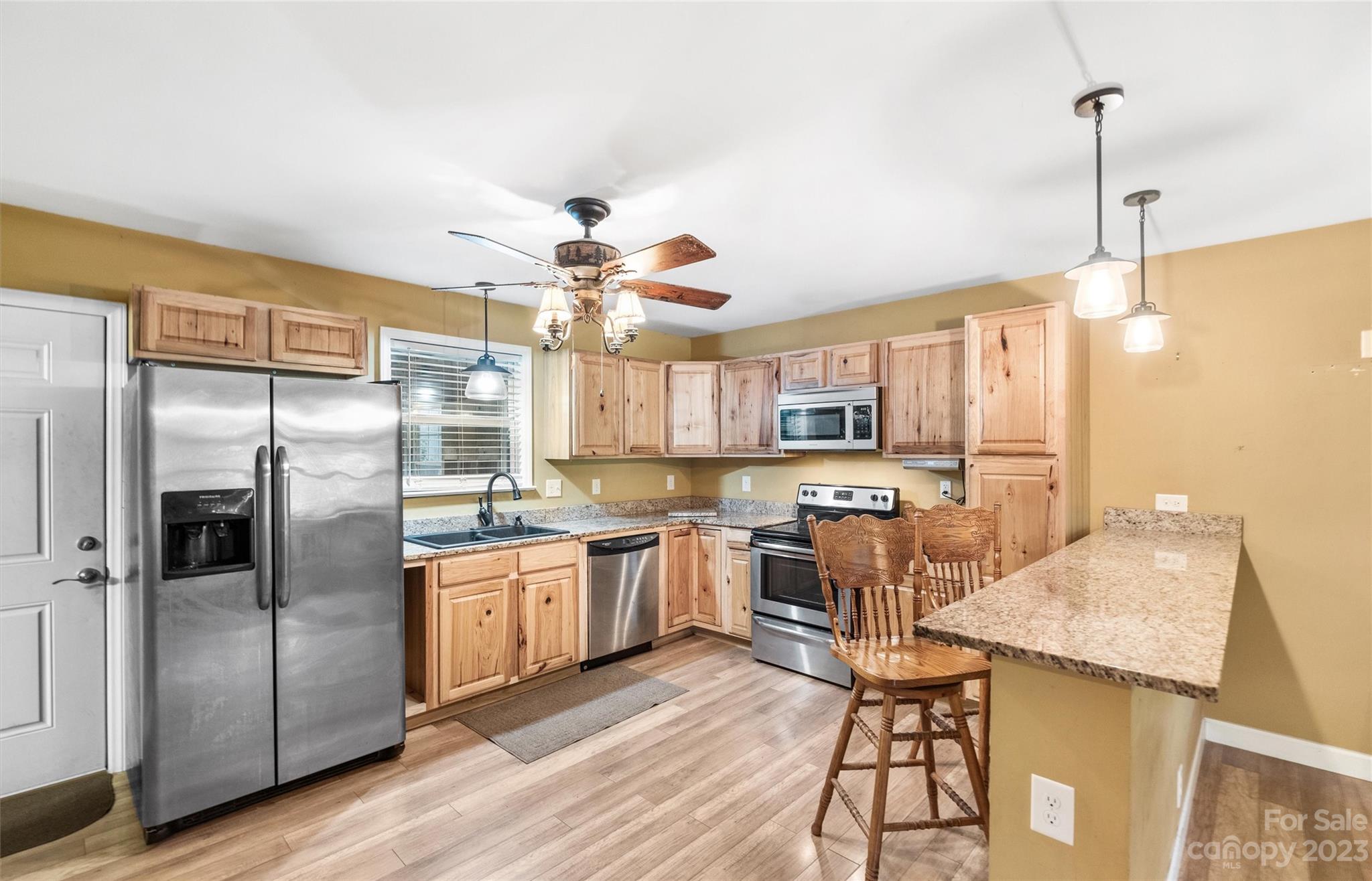 915 Harper Road Gastonia, NC 28056 - Photo 8 of 27 a kitchen with stainless steel appliances kitchen island granite countertop a refrigerator a stove a sink a dining table and chairs with wooden floor