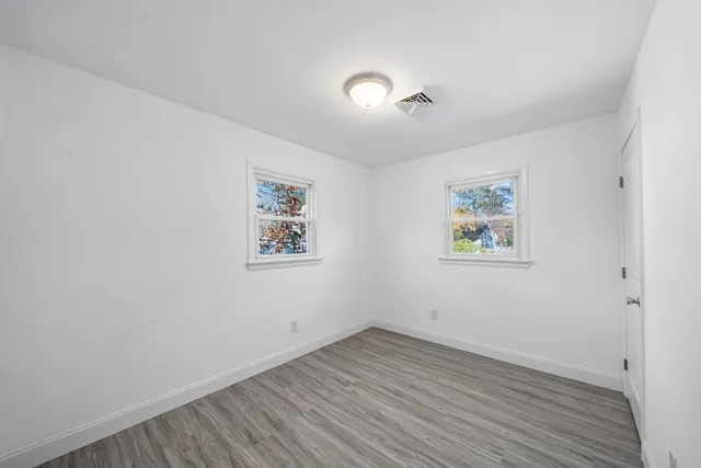 an empty room with wooden floor and window