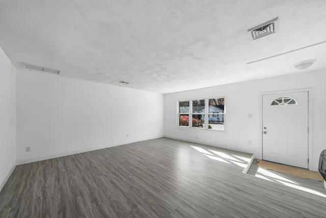 an empty room with wooden floor and windows