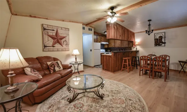 a living room with furniture a rug and kitchen chandelier