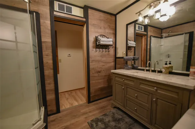 a bathroom with a granite countertop sink a mirror and a shower