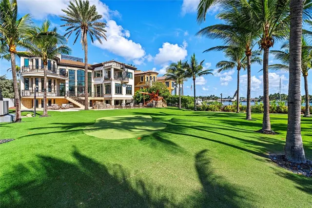 a view of a white house with a big yard and palm trees