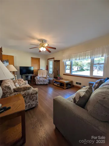 a living room with furniture and three large windows