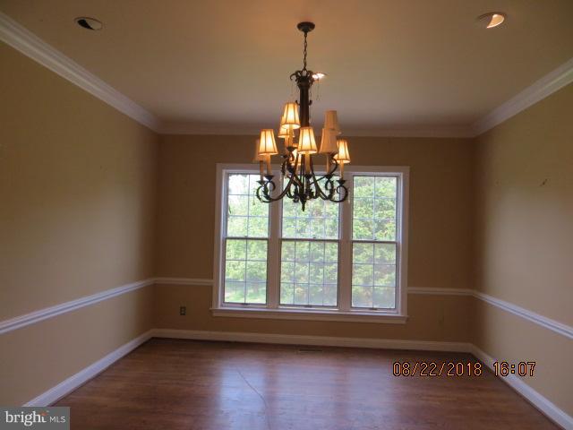 15621 Holly Grove Road Silver Spring, MD 20905 - Photo 8 of 21 a room with wooden floor chandelier and windows