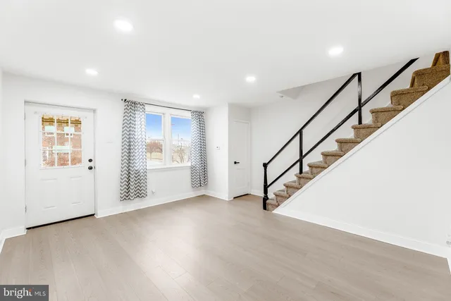 a view of an empty room with wooden floor and stairs
