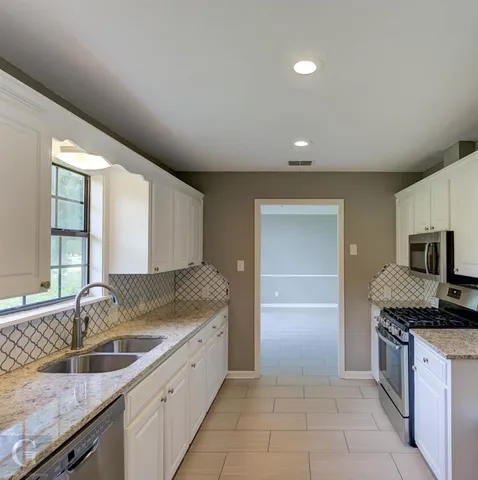 a kitchen with granite countertop a sink and a stove top oven