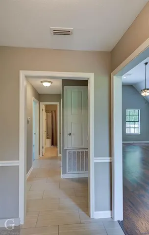 a view of a hallway with wooden floor and a living room