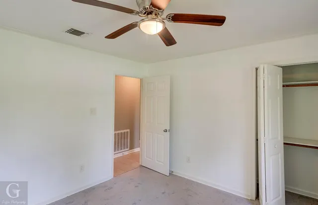 an empty room with closet and a chandelier fan