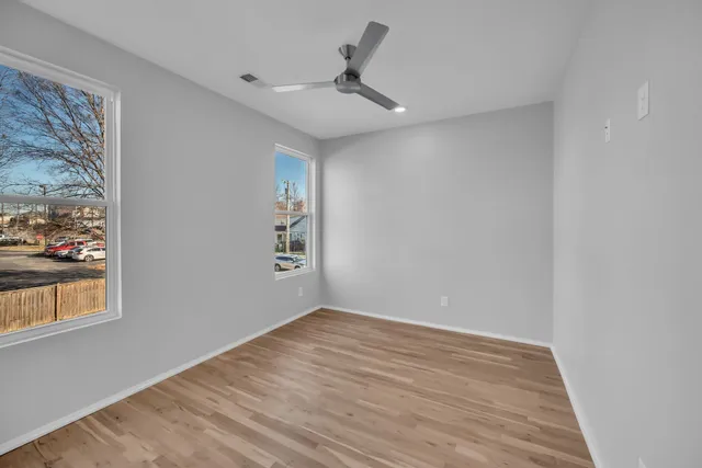 a view of an empty room with a window and wooden floor
