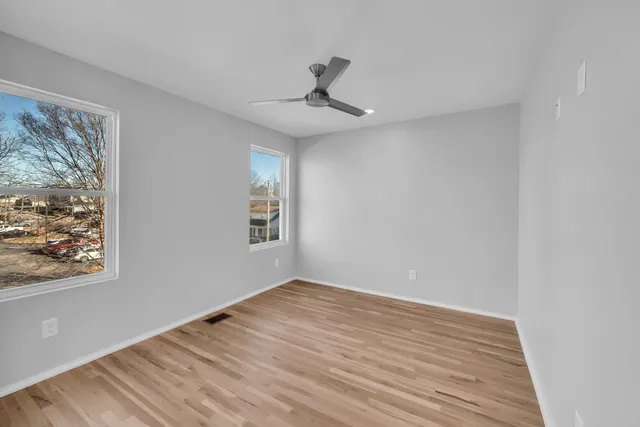 a view of empty room with wooden floor and fan