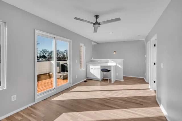 a living room with a balcony a ceiling fan and a rug