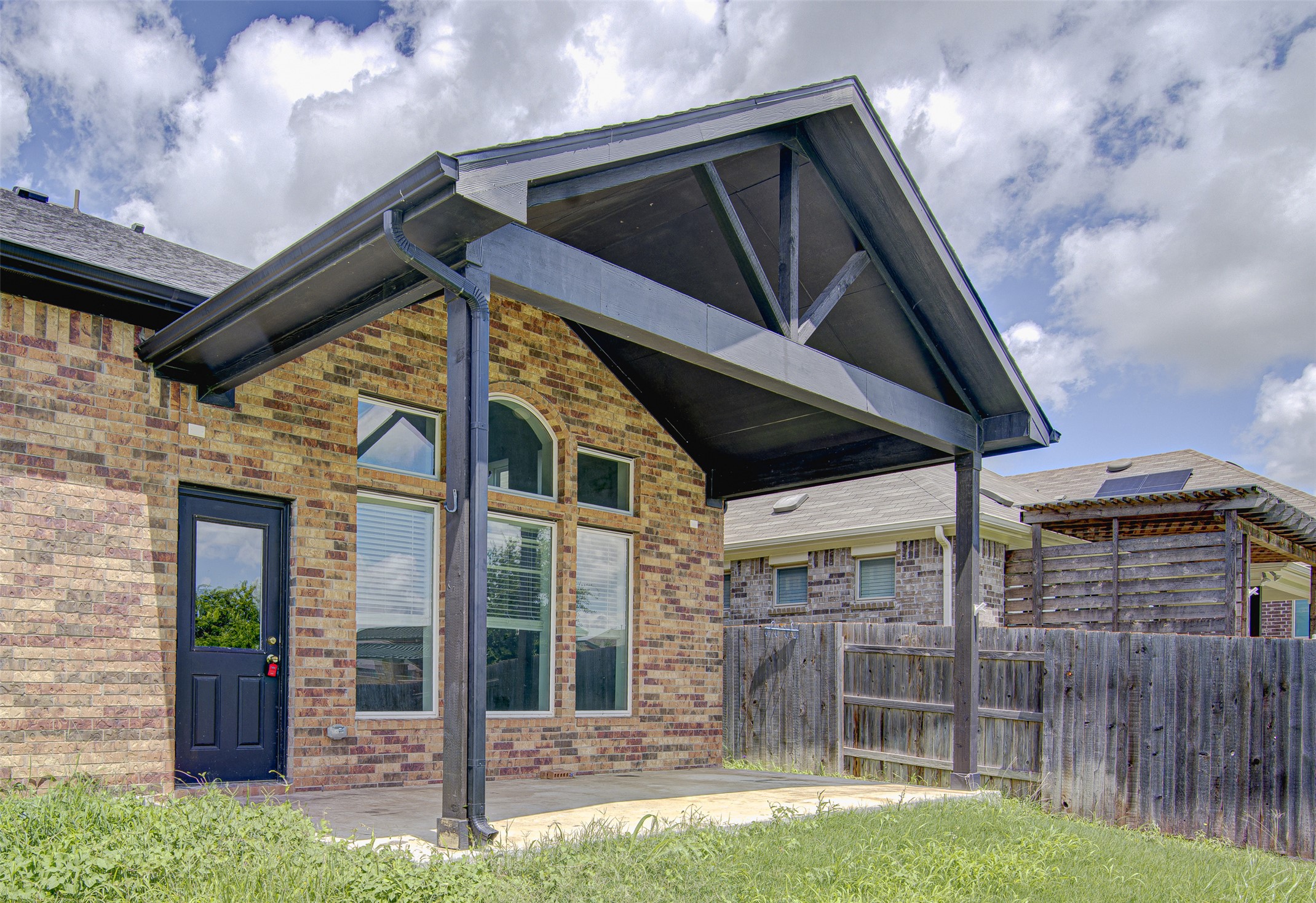 774 Cherrystone Loop Buda, TX 78610 - Photo 32 of 38 A spacious covered patio extends from the brick-clad home, offering a perfect outdoor retreat.