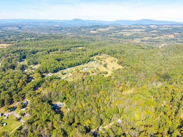 an aerial view of a houses with a yard and mountain
