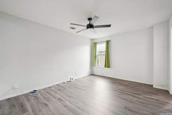 an empty room with wooden floor fan and windows