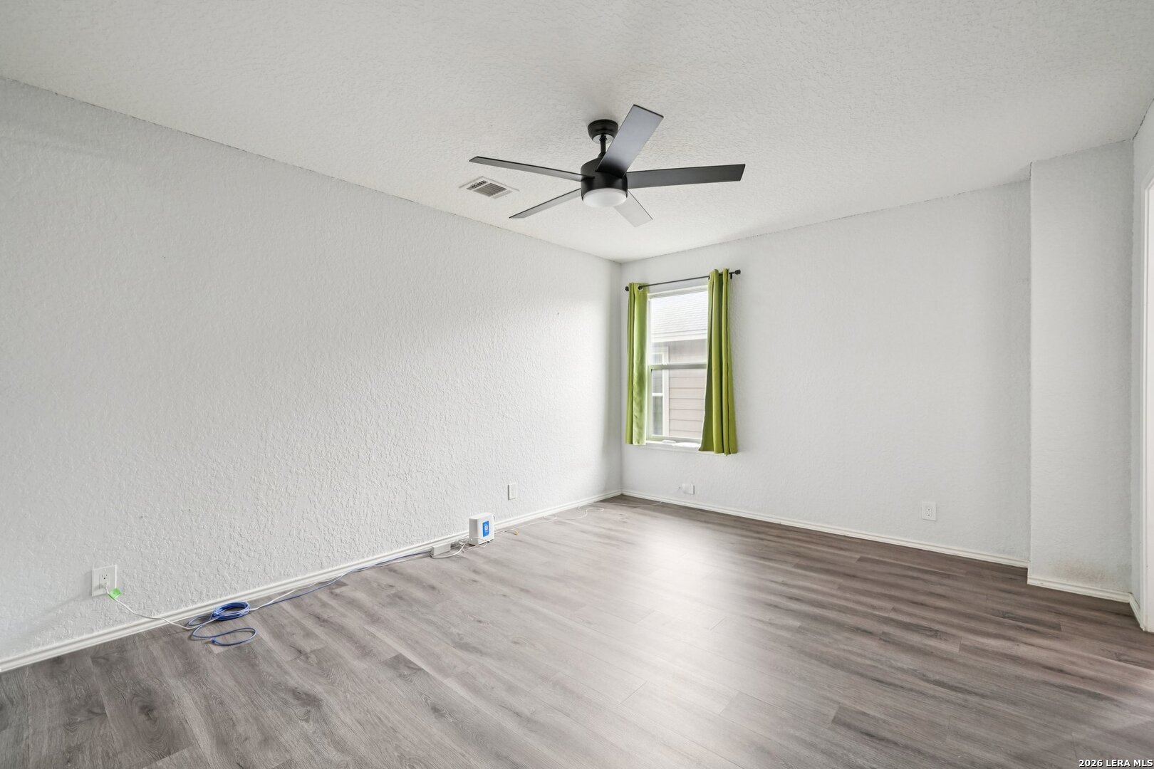 9536 Gold Stage Road San Antonio, TX 78254 - Photo 25 of 39 an empty room with wooden floor fan and windows