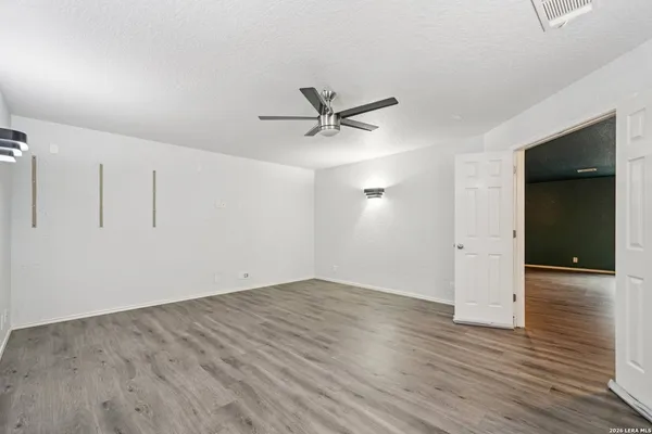 an empty room with wooden floor and a ceiling fan