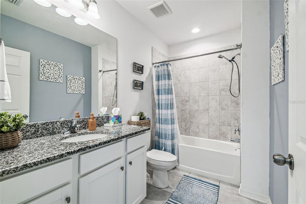 12907 Conquistador Loop Spring Hill, FL 34610 - Photo 36 of 74 a bathroom with a granite countertop sink a toilet and shower