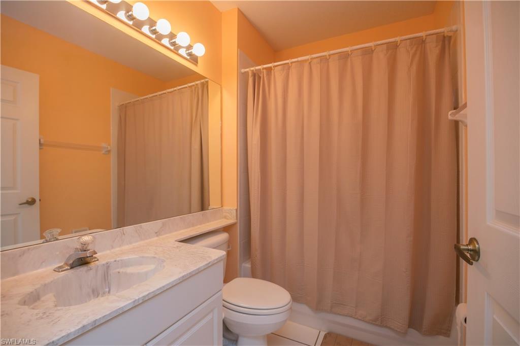 7870 Mahogany Run Lane, Unit 1713 Naples, FL 34113 - Photo 7 of 15 a bathroom with a sink a toilet and shower curtain