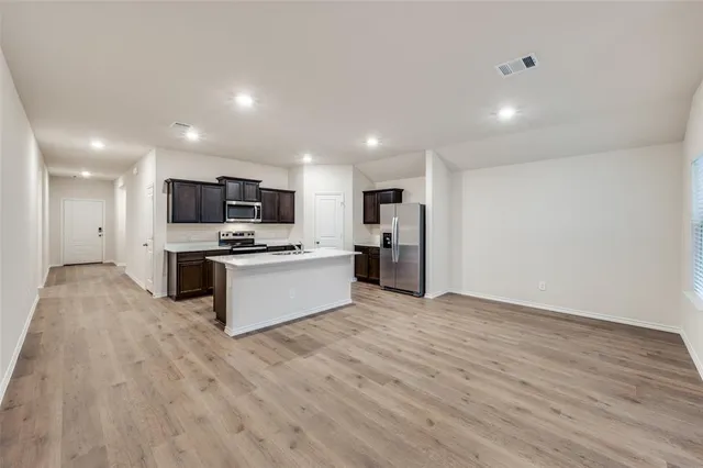 a large kitchen with stainless steel appliances granite countertop a stove a sink dishwasher and a refrigerator with wooden floor