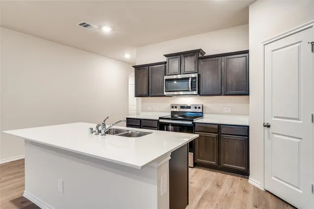 a kitchen with a sink a stove a refrigerator and white cabinets