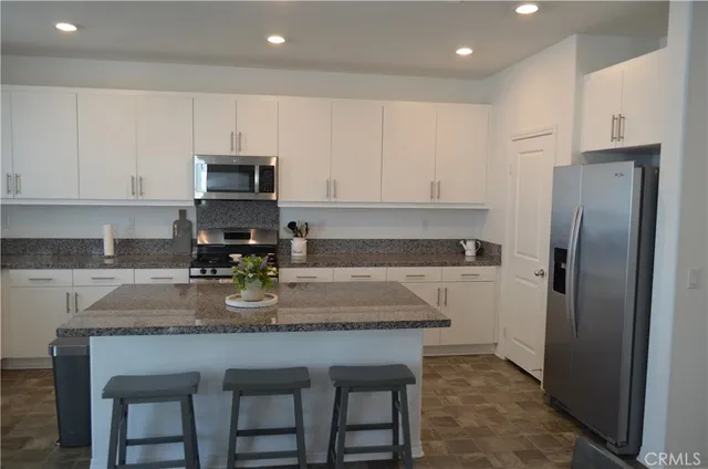 a kitchen with stainless steel appliances granite countertop a stove a refrigerator a sink a stove and white cabinets