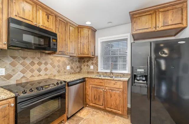 a kitchen with granite countertop cabinets stainless steel appliances and a window