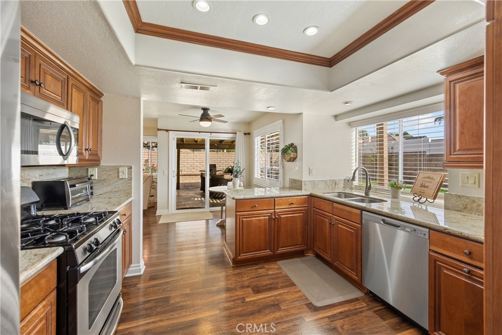 7051 Stanislaus Place Rancho Cucamonga, CA 91701 - Photo 22 of 57 a kitchen with stainless steel appliances granite countertop lots of counter top space and wooden floors