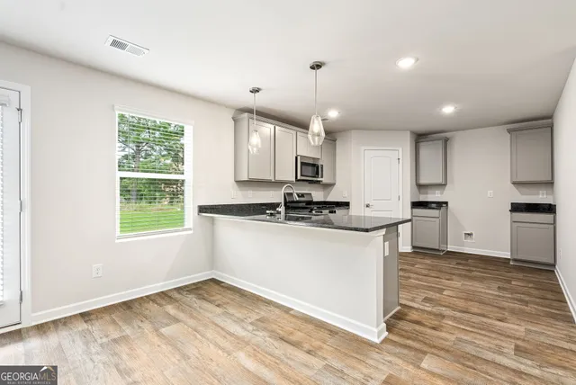 a kitchen with stainless steel appliances granite countertop a sink window and cabinets