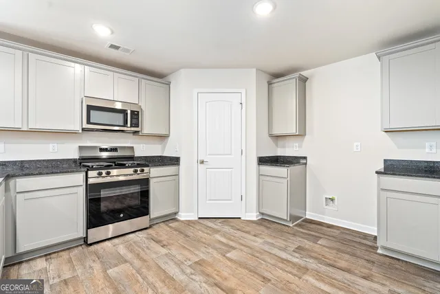 a kitchen with granite countertop a stove a sink and a refrigerator