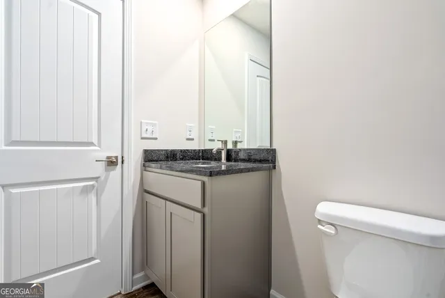 a bathroom with a granite countertop sink and a toilet