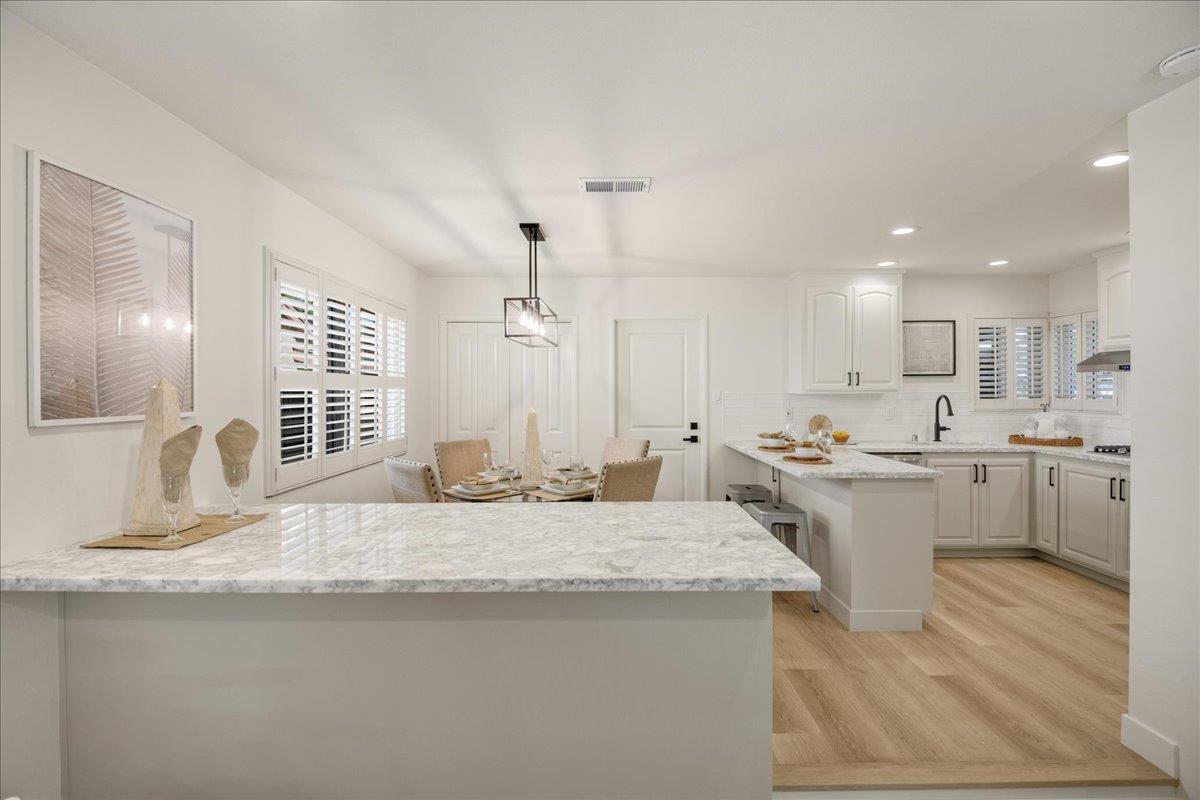 1069 Malott Drive San Jose, CA 95121 - Photo 10 of 32 a large white kitchen with a sink and dishwasher a stove a dining table with wooden floor