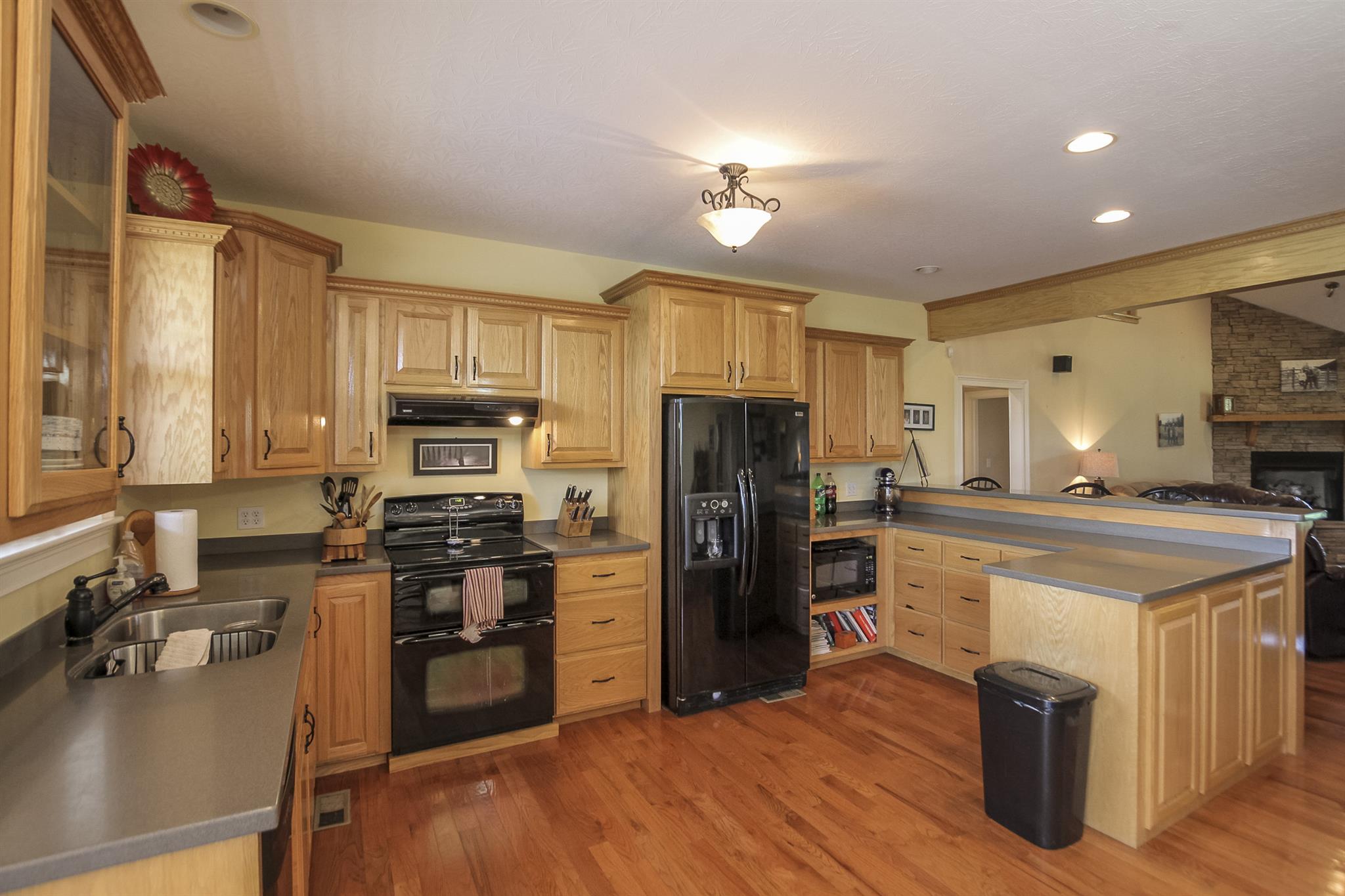 4599 Gamble Road Cedar Hill, TN 37032 - Photo 10 of 25 a kitchen with a refrigerator a stove top oven a sink dishwasher and wooden cabinets with wooden floor