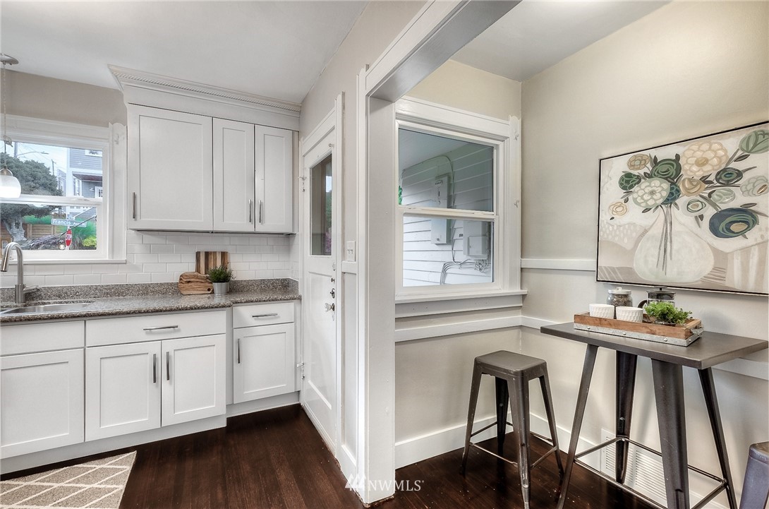 452 North 65th Street Seattle, WA 98103 - Photo 14 of 31 a kitchen with stainless steel appliances granite countertop a stove a sink and white cabinets with wooden floor