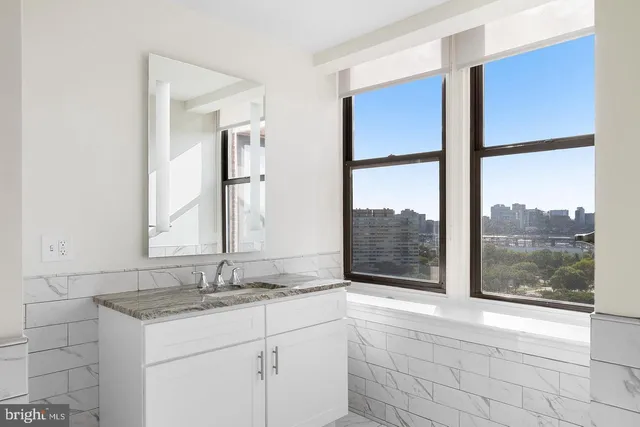 a bathroom with a granite countertop sink and a large mirror