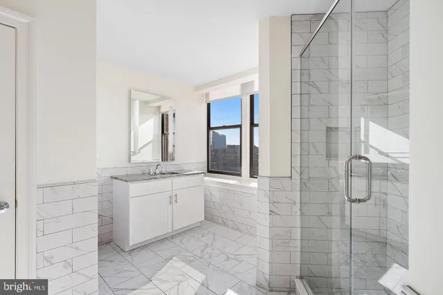 a bathroom with a granite countertop shower a sink and a mirror