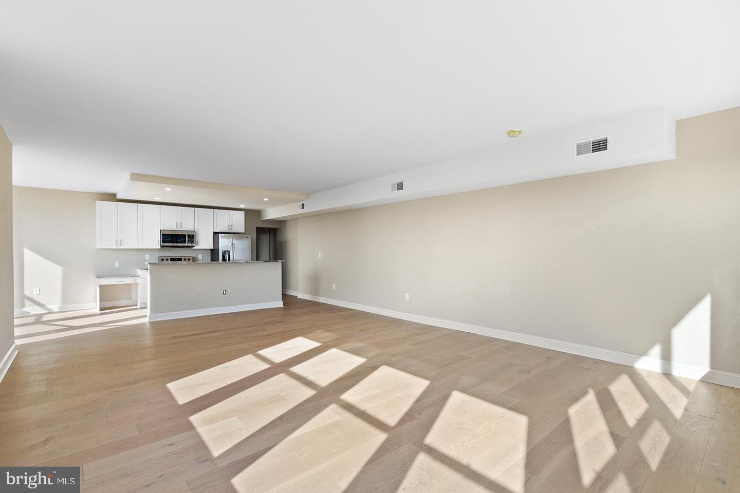 2201 Pennsylvania Avenue, Unit 1204B Philadelphia, PA 19130 - Photo 6 of 46 a view of kitchen and empty room with wooden floor