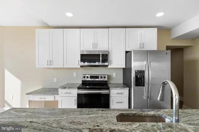 a kitchen with stainless steel appliances granite countertop a refrigerator a stove and a sink