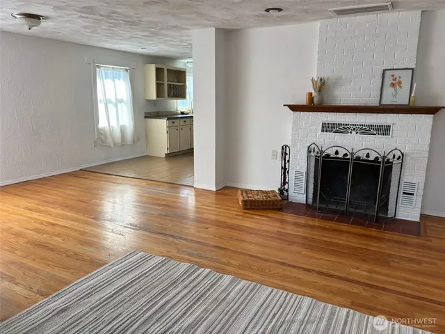 a view of a livingroom with wooden floor and a fireplace