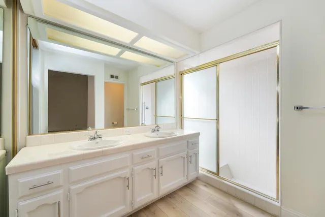 a bathroom with a double vanity sink and mirror with shower