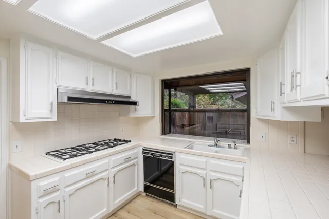a kitchen with granite countertop white cabinets and white appliances