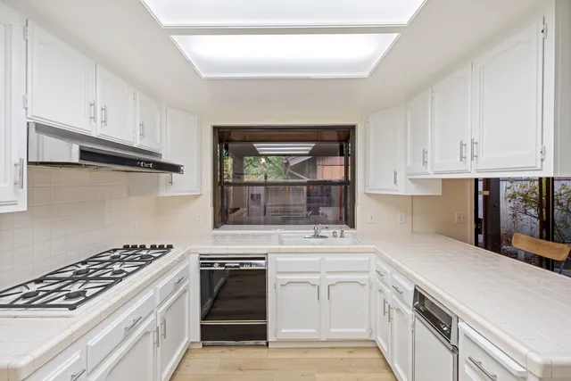 a kitchen with white cabinets and appliances