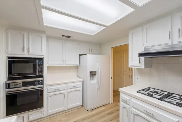 a kitchen with white cabinets and stainless steel appliances