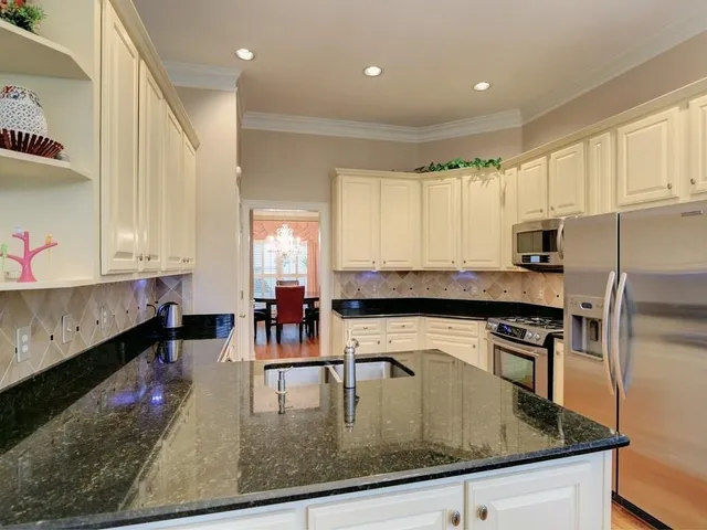 a kitchen with kitchen island granite countertop a stove top oven a sink a dining table and chairs