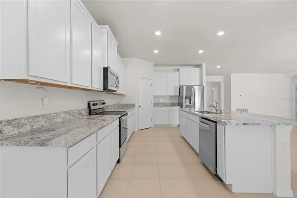 a large kitchen with stainless steel appliances granite countertop a sink and cabinets